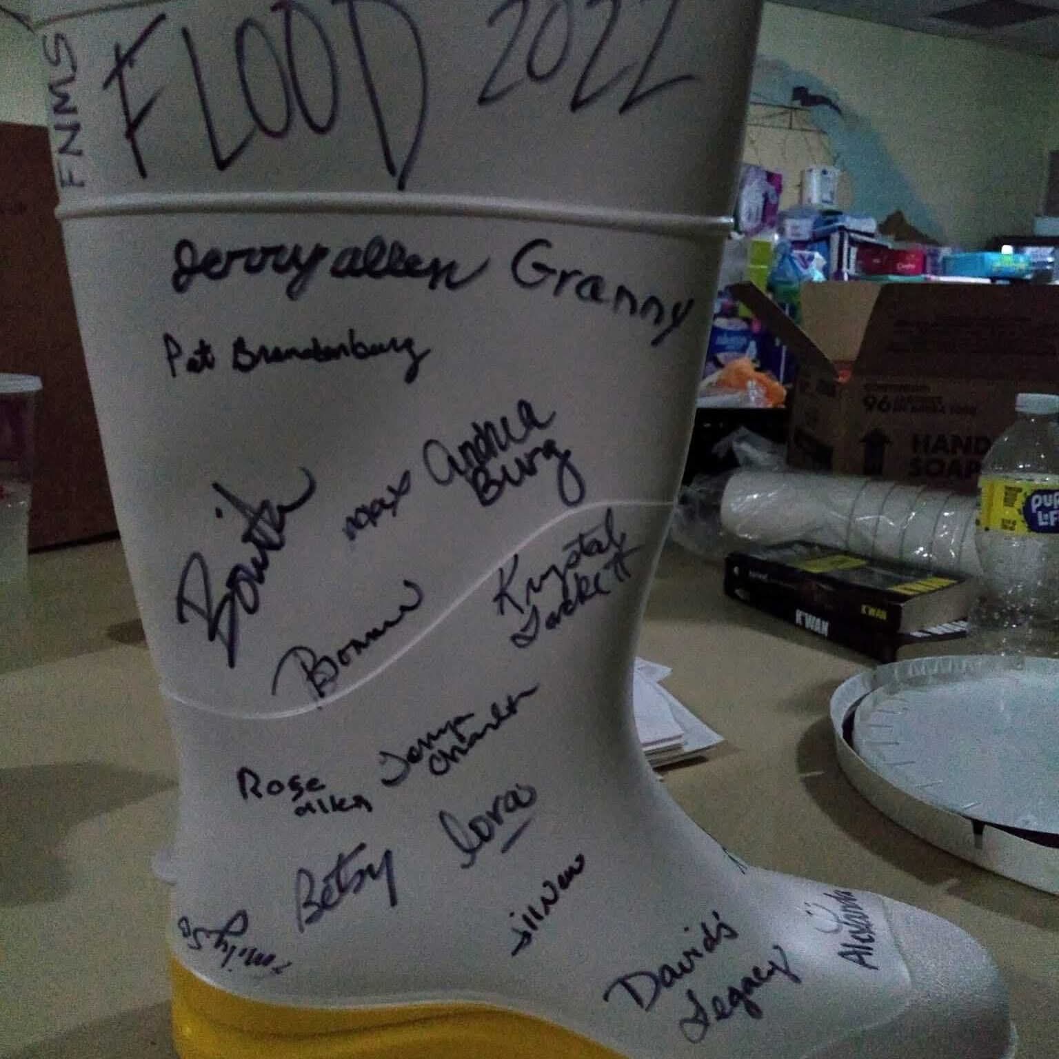 A white rain boot signed by flood relief volunteers, marked Flood 2022