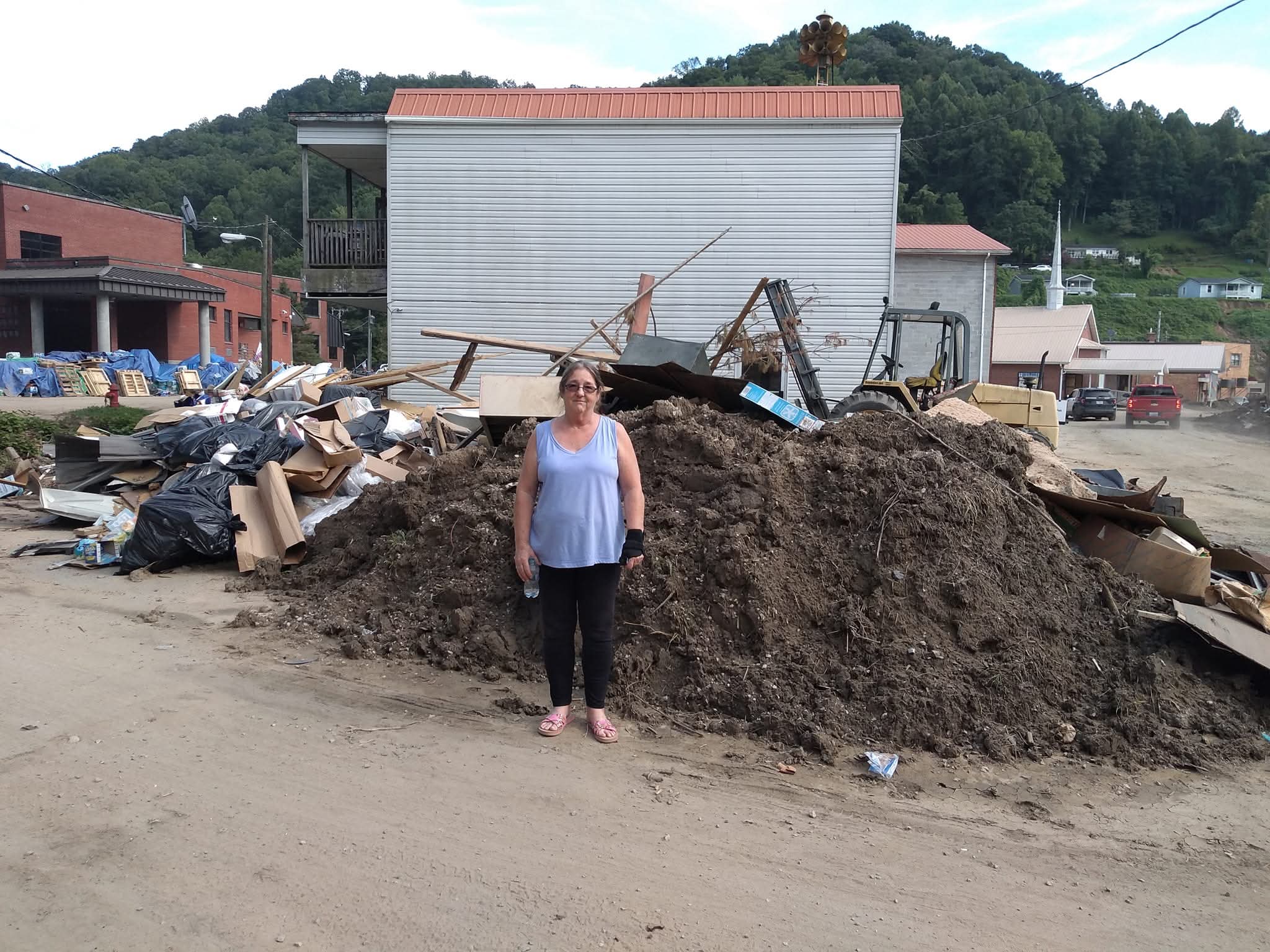 A community member standing beside debris piles during Eastern Kentucky flood cleanup